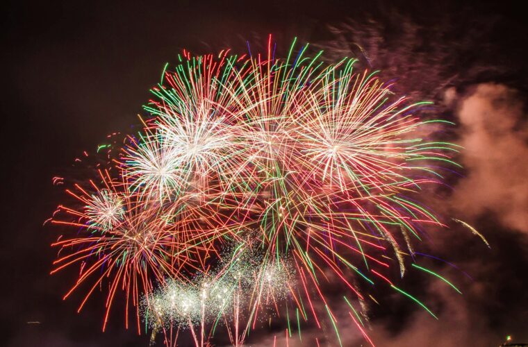 Colorful fireworks illuminating the night sky above a serene water body, creating a festive atmosphere.
