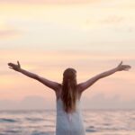 A woman enjoying a serene sunset on Unawatuna Beach, Sri Lanka, depicting peace and freedom.